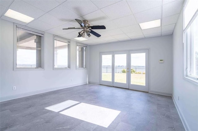 unfurnished room featuring baseboards, a ceiling fan, french doors, and a drop ceiling