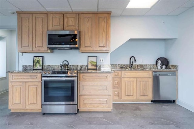 kitchen featuring stone counters, baseboards, stainless steel appliances, and a paneled ceiling