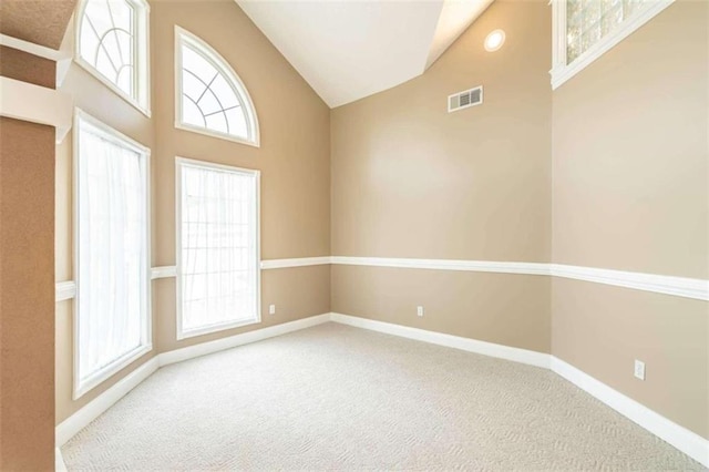 carpeted spare room with visible vents, baseboards, and vaulted ceiling