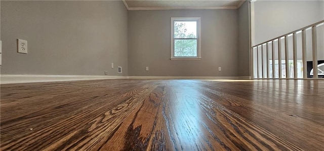 empty room featuring ornamental molding, baseboards, and wood finished floors