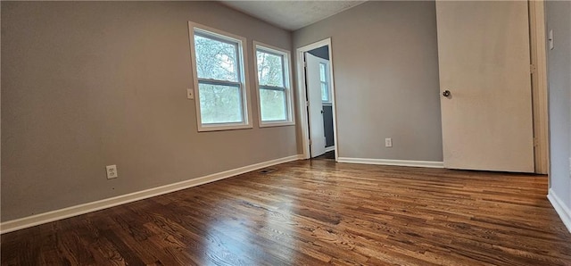 unfurnished room featuring baseboards and dark wood finished floors