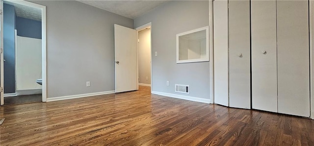 unfurnished bedroom with wood finished floors, visible vents, and baseboards