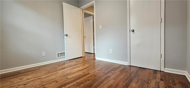 unfurnished bedroom featuring baseboards, a closet, visible vents, and wood finished floors