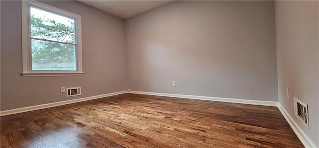 empty room with baseboards, visible vents, and dark wood-style flooring