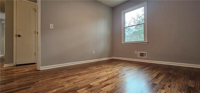 empty room featuring visible vents, baseboards, and dark wood-style flooring