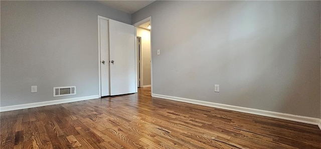 spare room featuring dark wood finished floors, visible vents, and baseboards