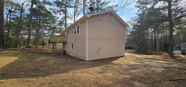 view of property exterior with central AC, a wooden deck, and driveway