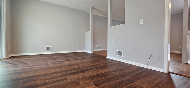 empty room with dark wood finished floors, visible vents, and baseboards