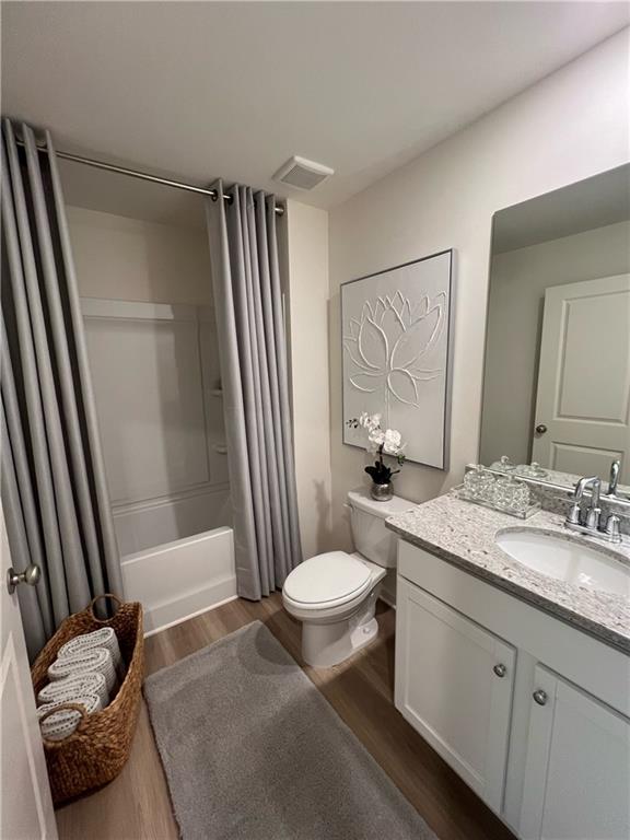 1567 Aiden Way Unit 34, Conyers, GA 30013 - full bath featuring wood finished floors, toilet, shower / bathtub combination with curtain, and vanity