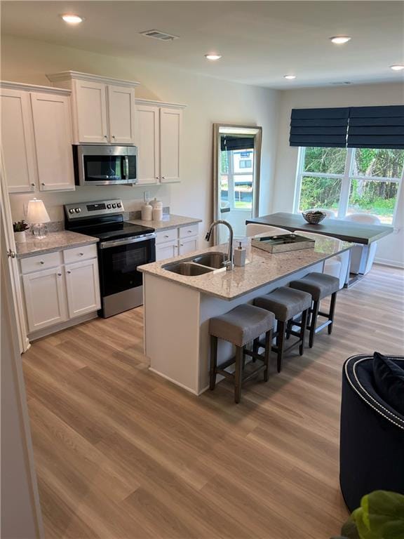 1567 Aiden Way Unit 34, Conyers, GA 30013 - kitchen featuring appliances with stainless steel finishes, a sink, a breakfast bar area, white cabinetry, and recessed lighting