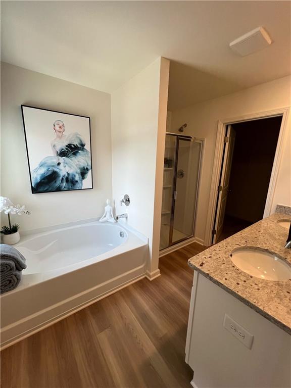 1567 Aiden Way Unit 34, Conyers, GA 30013 - bathroom featuring wood finished floors, a bath, a stall shower, double vanity, and baseboards