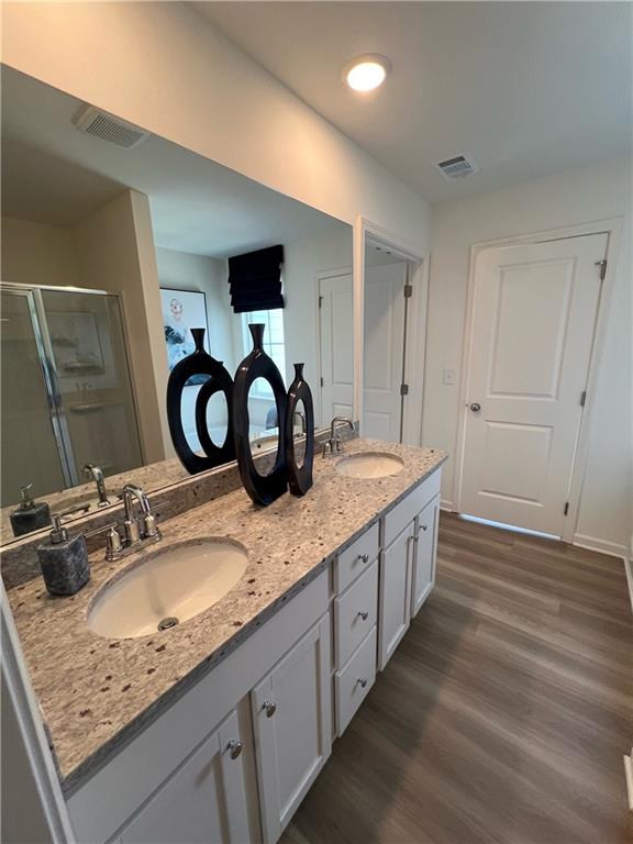 1567 Aiden Way Unit 34, Conyers, GA 30013 - bathroom featuring a shower stall, wood finished floors, and double vanity