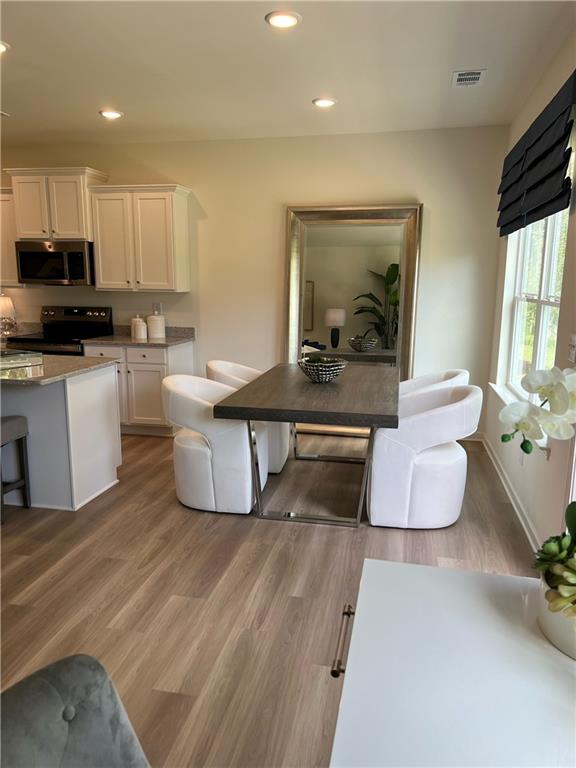1567 Aiden Way Unit 34, Conyers, GA 30013 - kitchen featuring appliances with stainless steel finishes, white cabinets, light wood finished floors, and recessed lighting