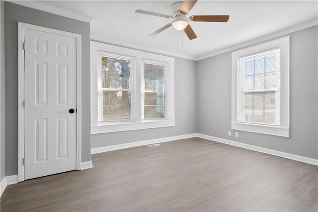 unfurnished room featuring dark hardwood / wood-style flooring, a wealth of natural light, crown molding, and ceiling fan