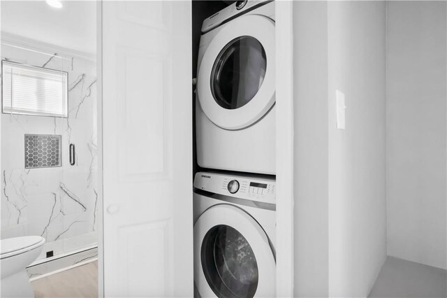 clothes washing area with stacked washing maching and dryer