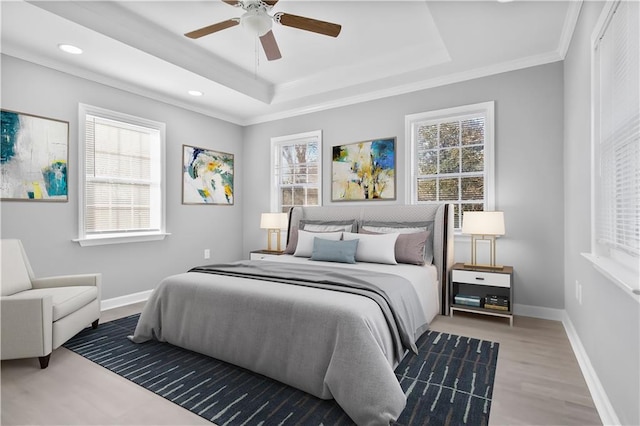 bedroom featuring a raised ceiling, multiple windows, ceiling fan, and hardwood / wood-style flooring