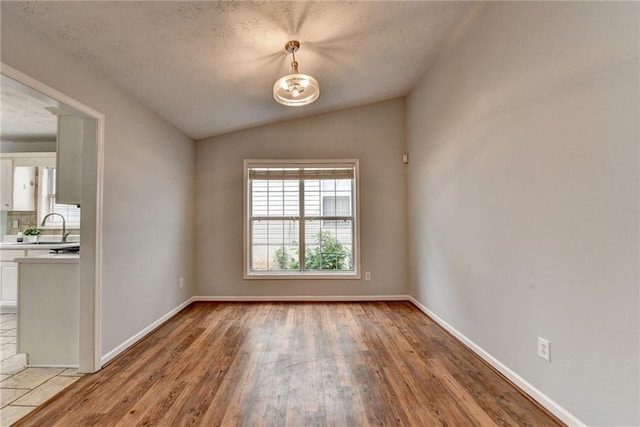 1965 Sterling Creek Ct, Snellville, GA 30078 - spare room featuring lofted ceiling, light wood-style floors, a textured ceiling, baseboards, and a sink