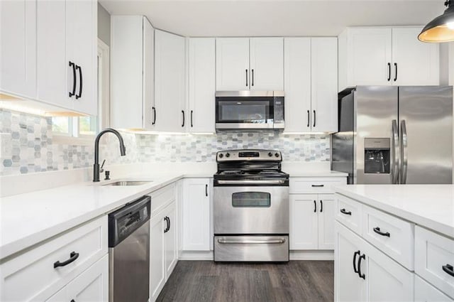 kitchen featuring hanging light fixtures, sink, white cabinets, and appliances with stainless steel finishes