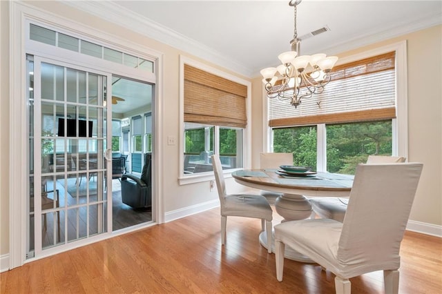 dining space with a chandelier, baseboards, healthy amount of natural light, crown molding, and light wood finished floors