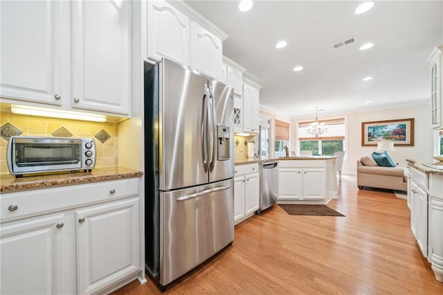 kitchen featuring stainless steel appliances, a peninsula, white cabinetry, tasteful backsplash, and light wood-type flooring