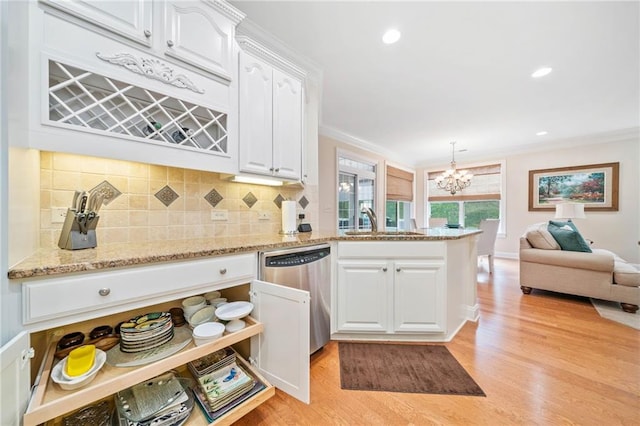 kitchen featuring stainless steel dishwasher, a sink, a chandelier, white cabinets, and a peninsula