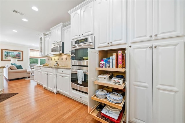 kitchen featuring stainless steel appliances, white cabinetry, light wood-style floors, recessed lighting, and tasteful backsplash