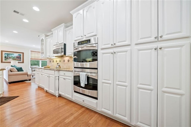 kitchen featuring stainless steel appliances, light wood-style flooring, white cabinets, recessed lighting, and backsplash
