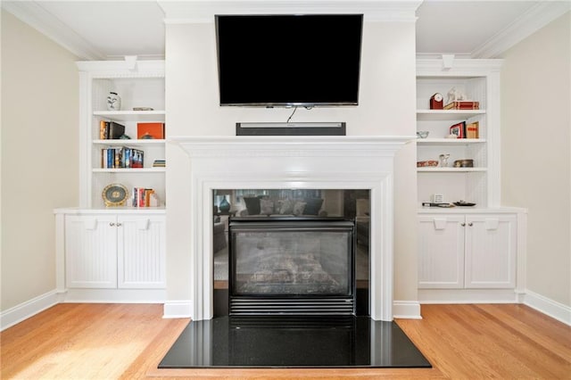 detailed view of wood finished floors, ornamental molding, baseboards, and built in shelves