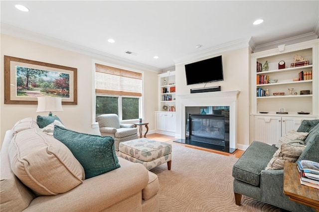 living area featuring ornamental molding, recessed lighting, a glass covered fireplace, light wood-style flooring, and baseboards