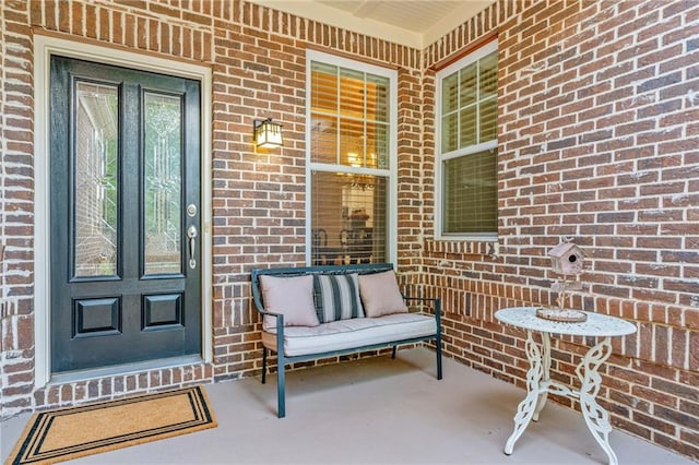 doorway to property featuring brick siding and a porch