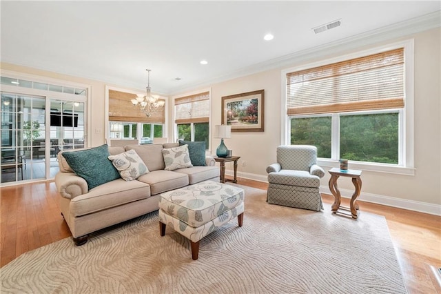 living area featuring a chandelier, light wood-type flooring, ornamental molding, baseboards, and recessed lighting