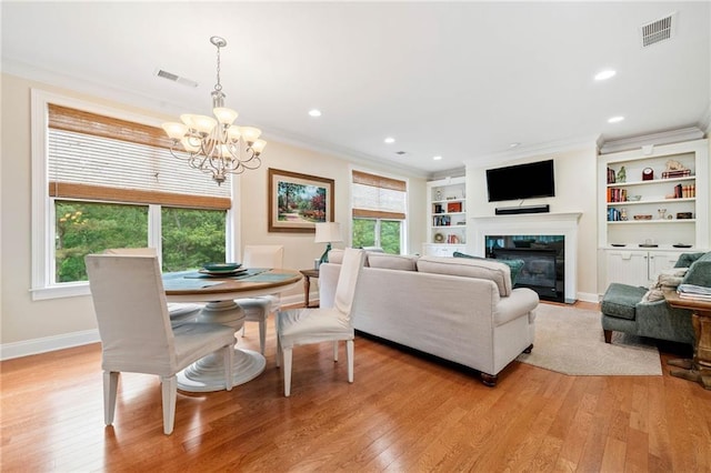 living room featuring a chandelier, crown molding, light wood-style flooring, healthy amount of natural light, and recessed lighting