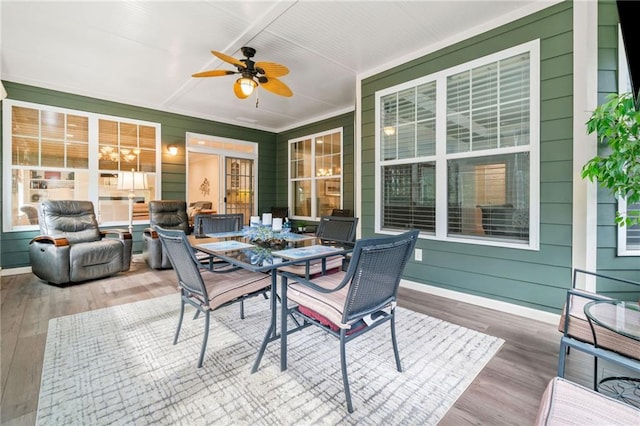 sunroom / solarium featuring ceiling fan, wood finished floors, and outdoor dining area