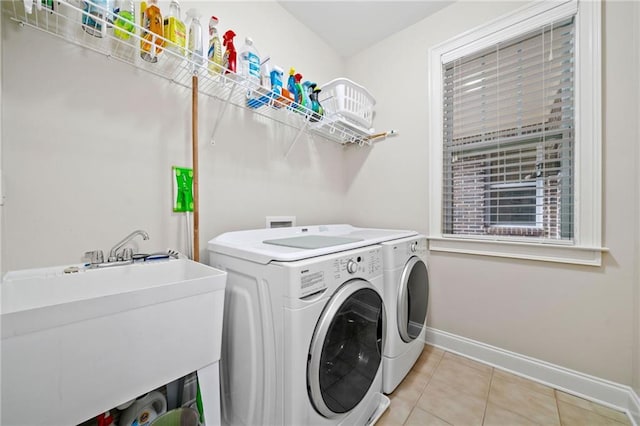laundry room featuring separate washer and dryer, baseboards, and light tile patterned floors