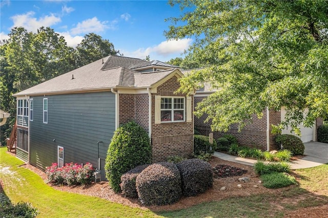 view of property exterior featuring brick siding, a lawn, and a garage