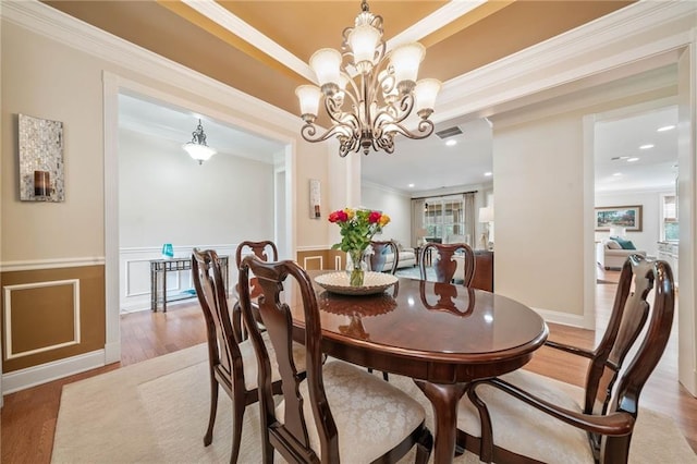 dining area with light wood-type flooring, wainscoting, a chandelier, crown molding, and recessed lighting