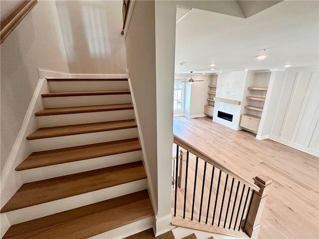 staircase featuring built in shelves, baseboards, a fireplace, recessed lighting, and wood finished floors