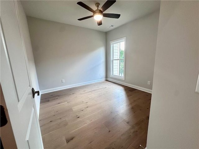 unfurnished room featuring baseboards, a ceiling fan, visible vents, and hardwood / wood-style flooring