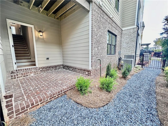 entrance to property with a patio area, fence, and brick siding