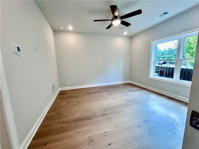 spare room featuring baseboards, wood-type flooring, a ceiling fan, and visible vents