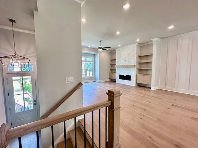unfurnished living room with ornamental molding, light wood-type flooring, recessed lighting, and ceiling fan with notable chandelier