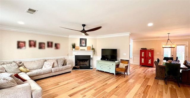 living room featuring crown molding, light hardwood / wood-style flooring, and ceiling fan