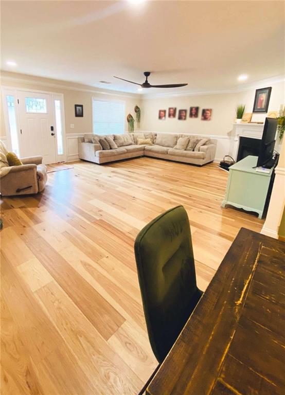 living room with wood-type flooring, crown molding, and ceiling fan