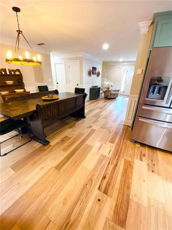 kitchen with decorative light fixtures, ornamental molding, green cabinets, light hardwood / wood-style floors, and stainless steel fridge with ice dispenser