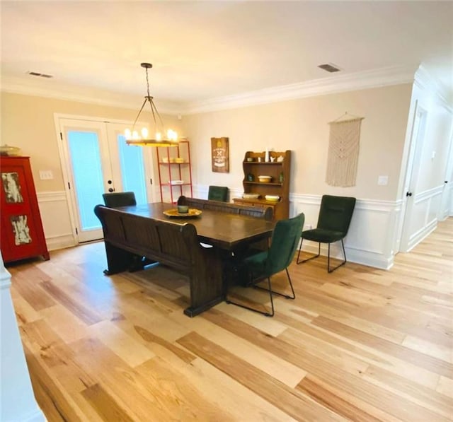 dining space featuring a notable chandelier, ornamental molding, and light wood-type flooring