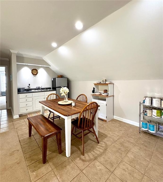 dining room featuring light tile patterned flooring, ornamental molding, lofted ceiling, and sink