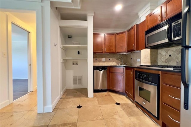 2285 Peachtree Rd NE Unit 1202, Atlanta, GA 30309 - kitchen featuring stainless steel appliances, decorative backsplash, light tile patterned flooring, dark countertops, and brown cabinetry