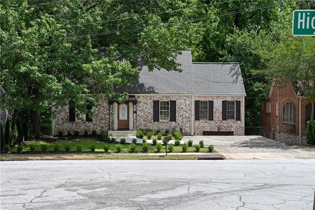 cape cod-style house featuring brick siding and a shingled roof