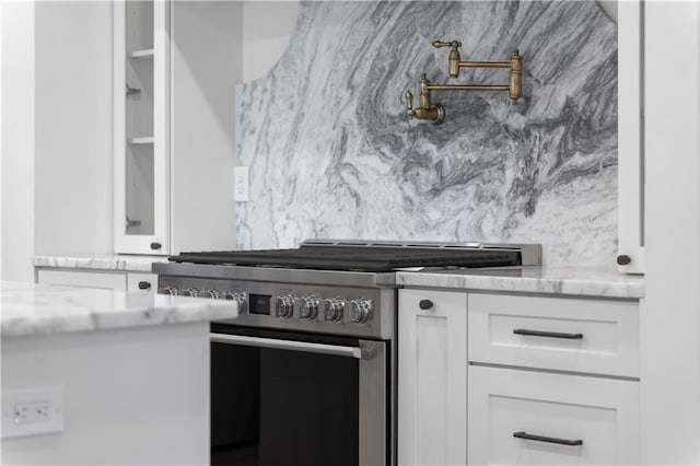 kitchen with stainless steel range, white cabinetry, and light stone countertops