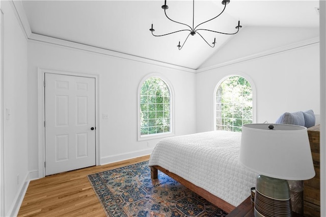 bedroom with a chandelier, vaulted ceiling, multiple windows, light wood finished floors, and baseboards